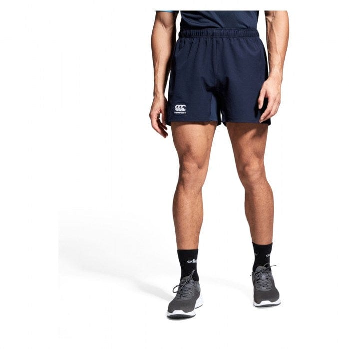 A person wearing Canterbury Yokohama rugby shorts from the Bundle Canterbury 3-Pack, black socks, and gray sneakers stands against a plain white background.