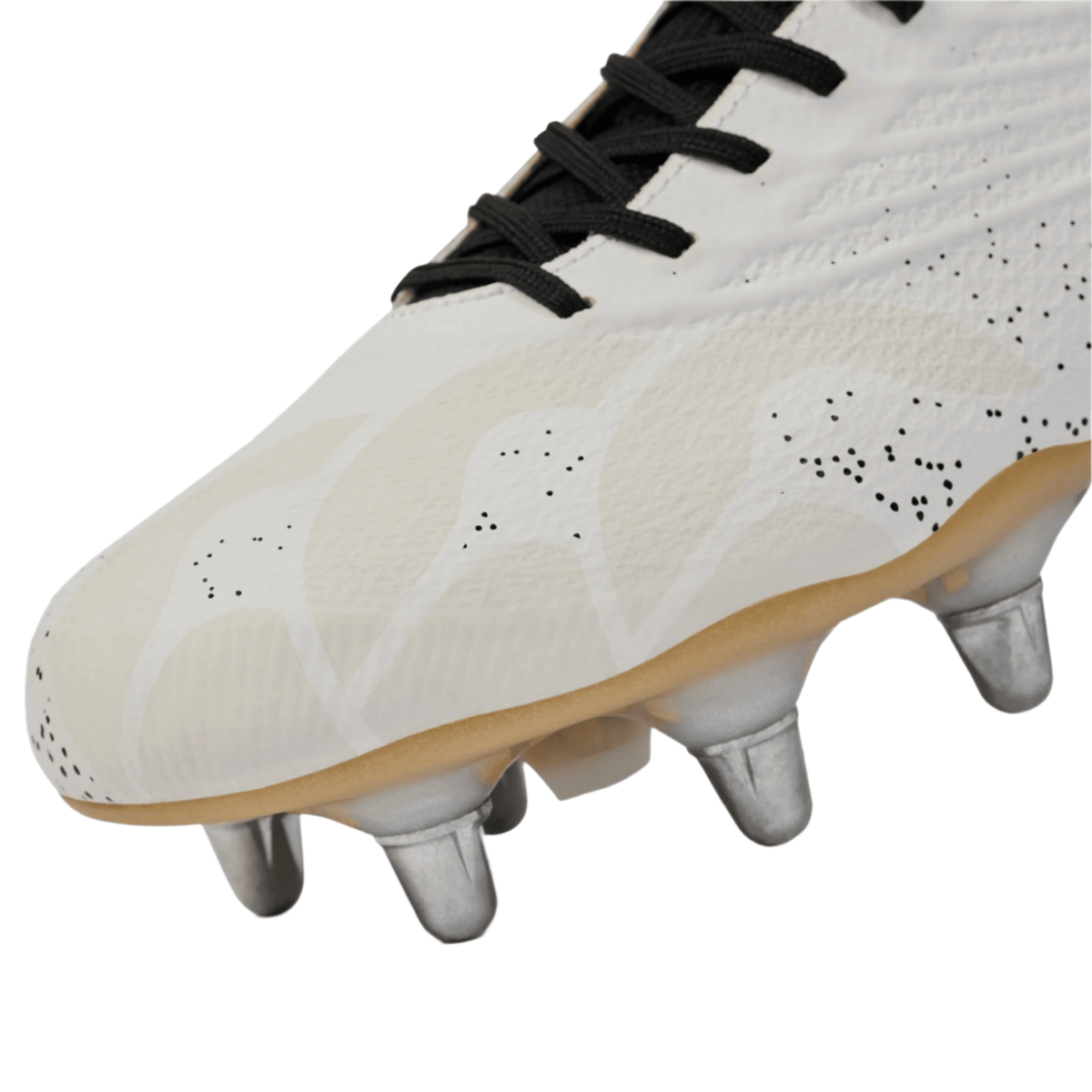 Close-up of the Canterbury Stampede Groundbreak Elite SG - White: a soccer cleat with black laces, textured upper, metallic studs, and light brown sole, echoing traditional soft ground rugby boot design from Canterbury.