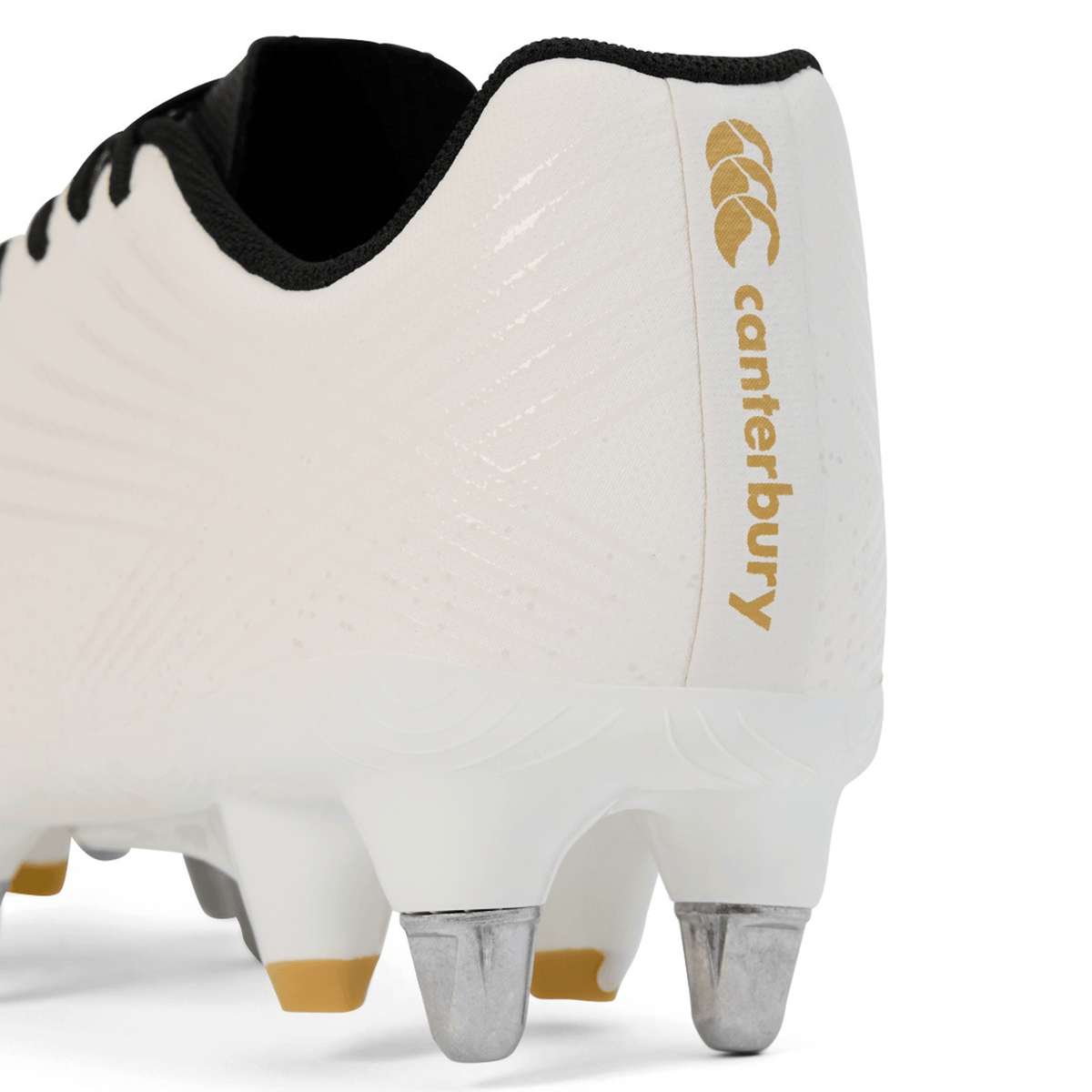 Close-up of the heel and metal studs on the Canterbury Stampede Groundbreak Team SG rugby boot in white, featuring black laces and gold Canterbury branding on the side.