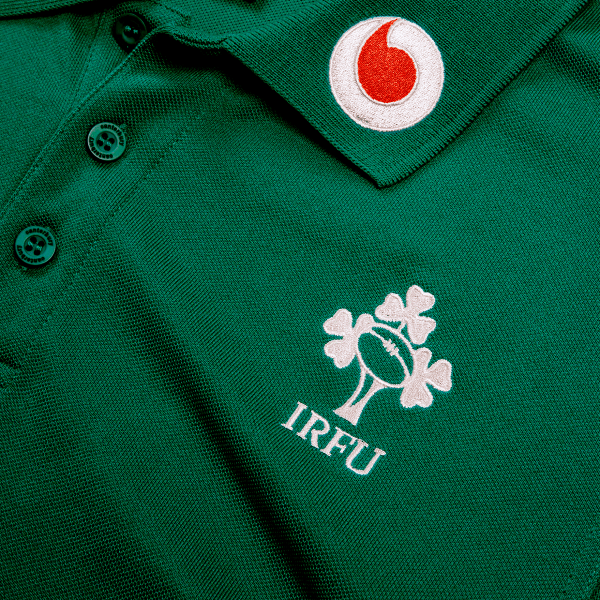 The Ireland 25/26 Team Polo by Canterbury features the IRFU logo, rugby ball, shamrock, and a red Vodafone logo on the collar—ideal for training or displaying your team pride.