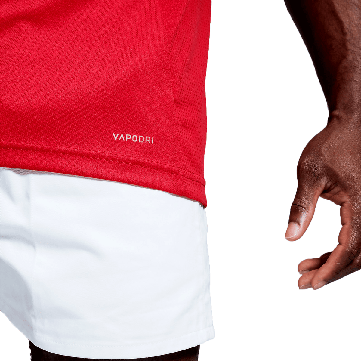 A close up of a person wearing a Canterbury Club Dry Singlet in red, and white shorts.