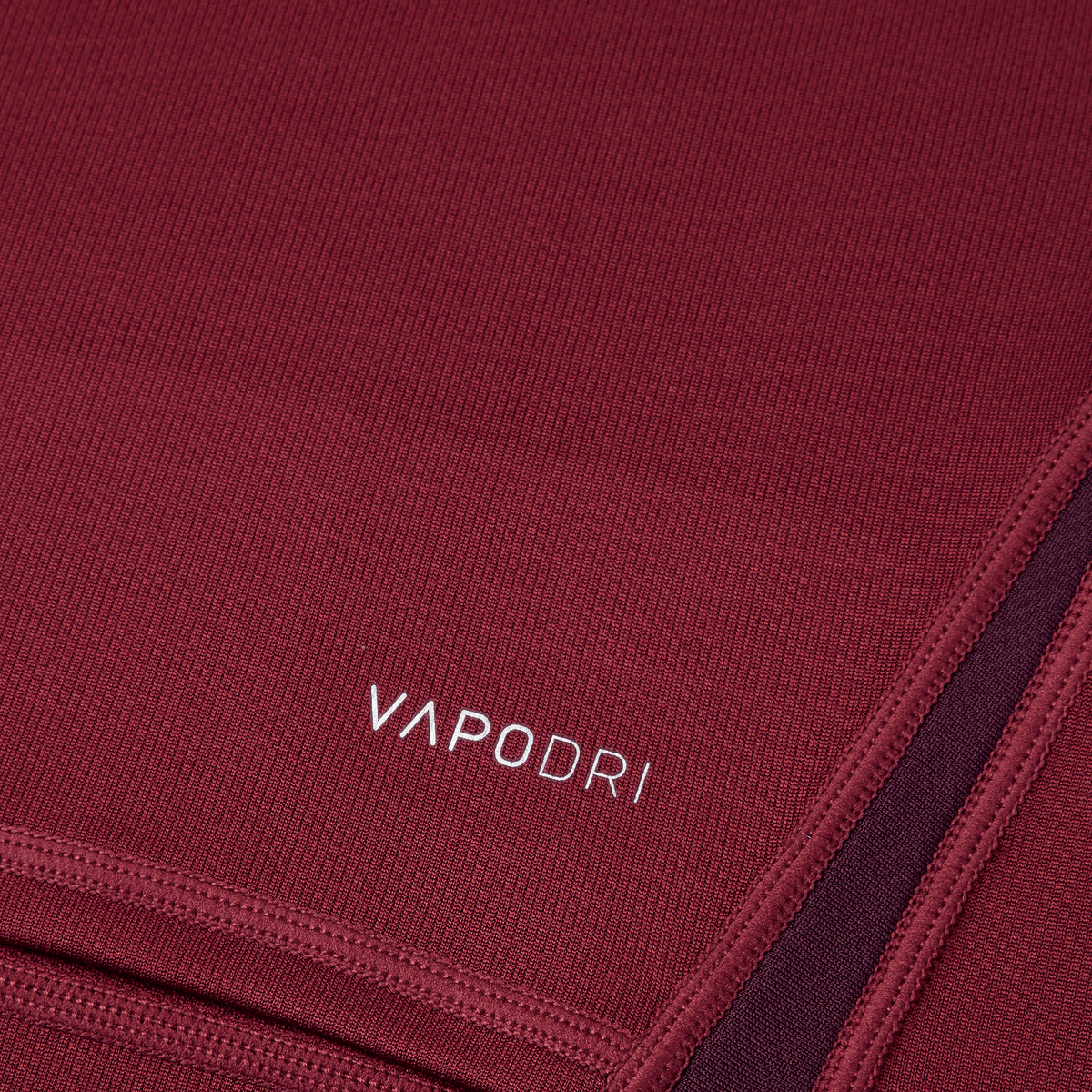 Close-up of a Canterbury Vapodri Evader Jersey in maroon fabric with "VAPODRI" text in white, featuring visible stitching and seams, showcasing its moisture-wicking technology.