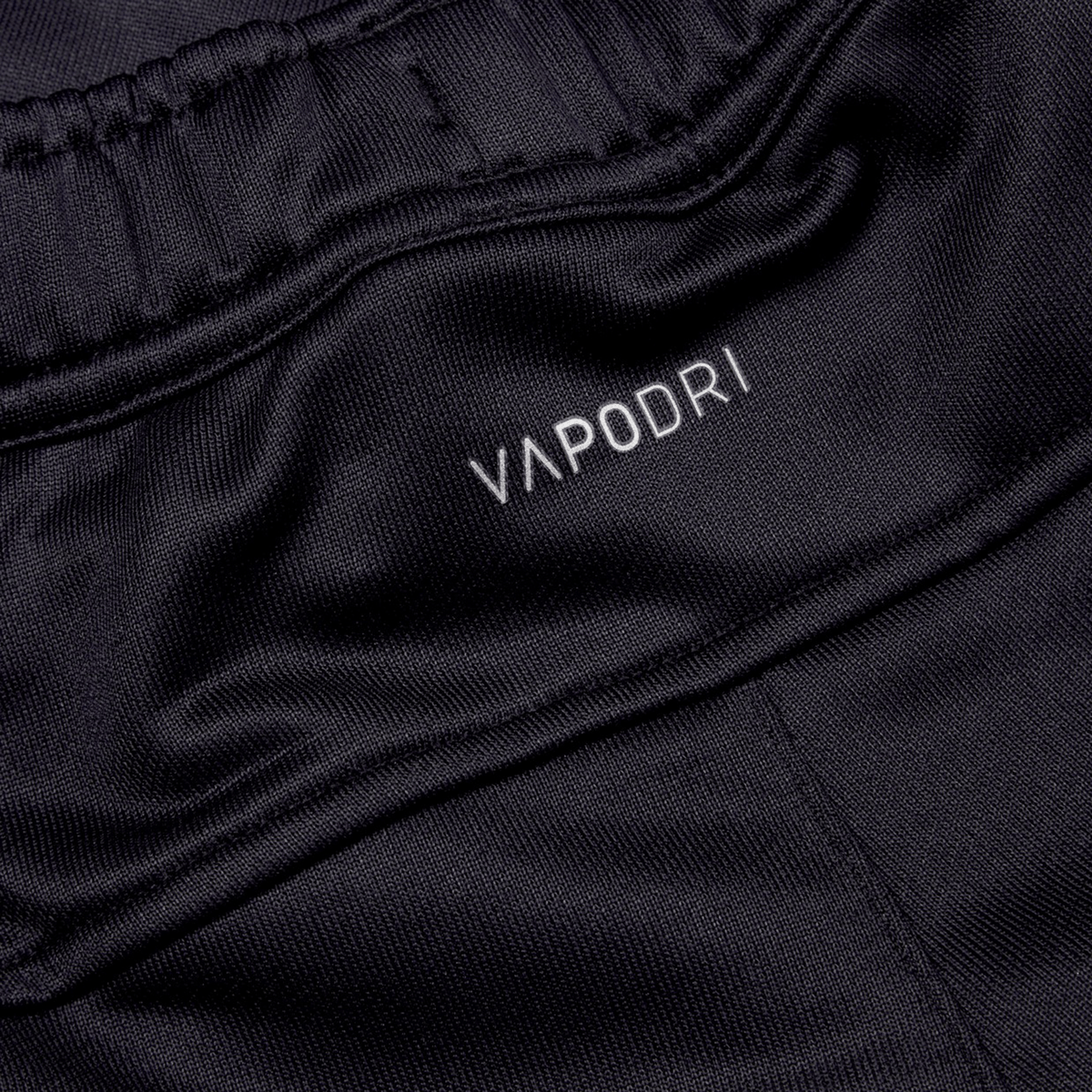 Close-up of the black athletic fabric labeled &quot;Canterbury,&quot; showcasing an elastic waistband and smooth, breathable texture. Perfect for the Irish rugby fan, these Ireland 24 Poly Knit Pants by Canterbury incorporate VapoDri technology, ensuring comfort during intense matches.