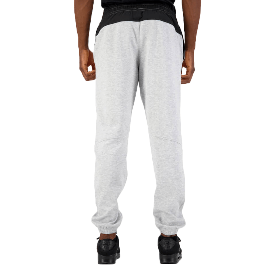 Rear view of a person wearing gray Canterbury Tempo Vapodri Hybrid Cuffed Pant sweatpants and black sneakers.