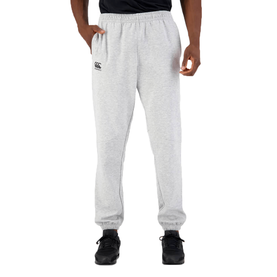 Man in gray Canterbury Tempo Vapodri Hybrid Cuffed Pants and black sneakers, standing with legs slightly apart, facing forward from the waist down.