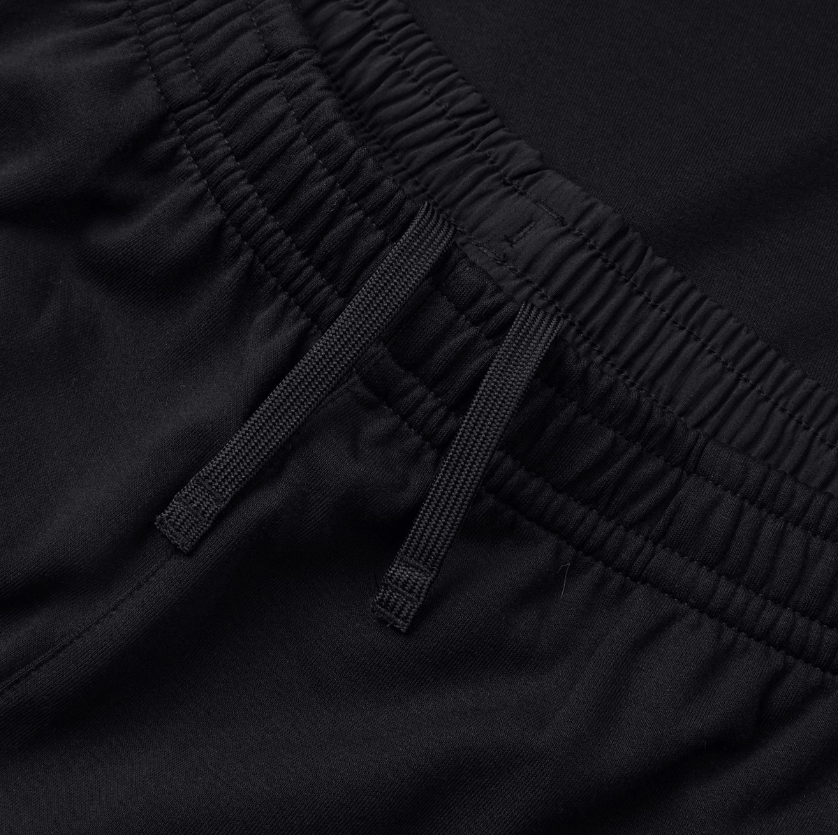 Close-up of the black elasticated waistband with two drawstrings on the Canterbury Tempo Vapodri Hybrid Cuffed Pant.