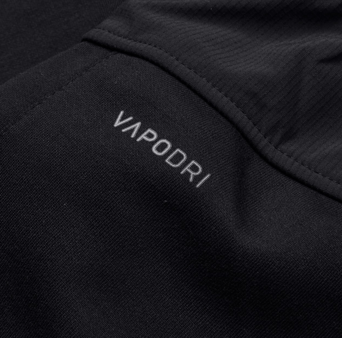 Close-up of the black fabric from the Canterbury Tempo Vapodri Hybrid Cuffed Pant, showcasing an elastic waistband with "VAPODRI" subtly printed in white.