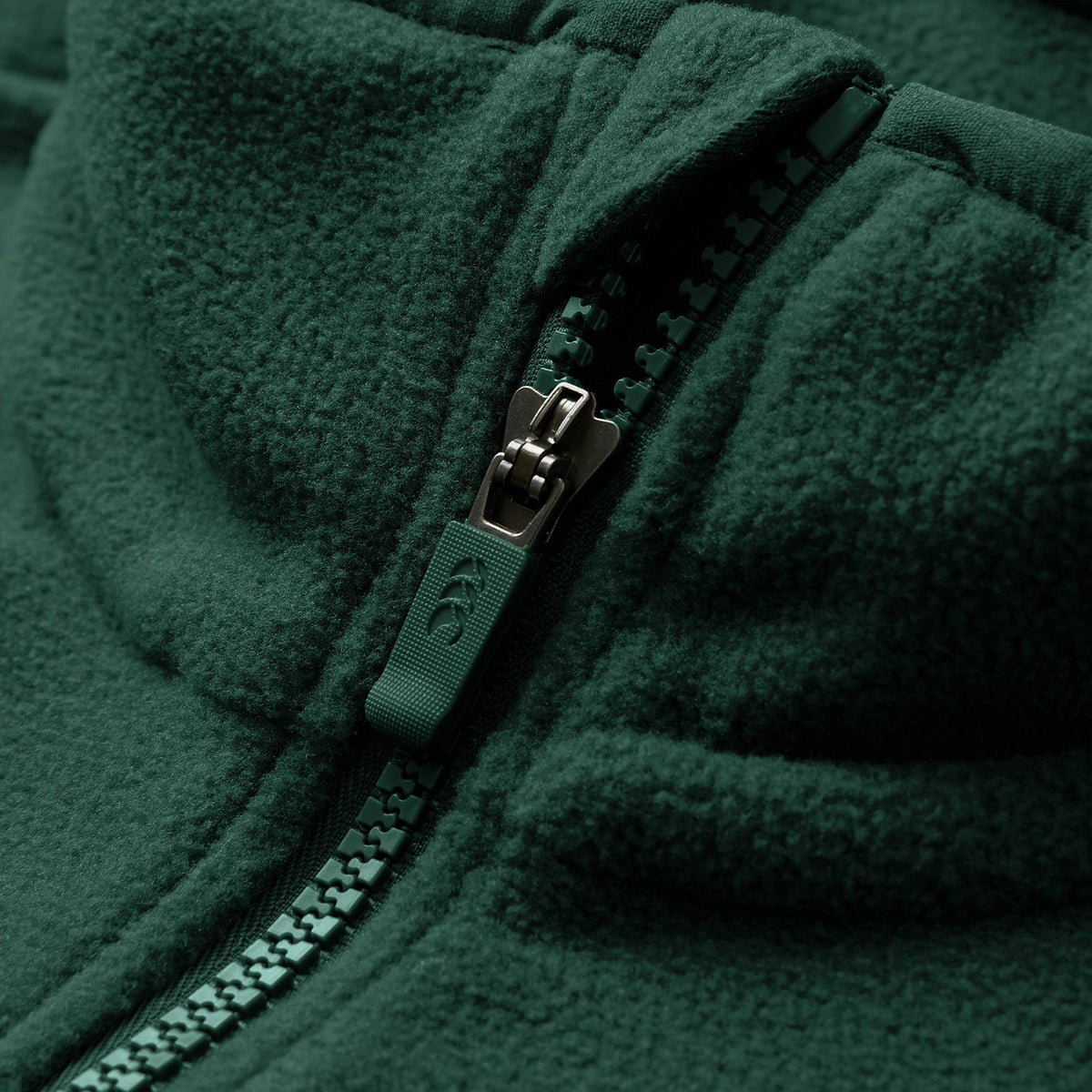 Close-up of the Canterbury Ireland 26 Retro Fleece 1/4 Zip, featuring its distinctive green fabric with a partially closed plastic zipper that highlights the texture and detailing of both the fleece and the zipper.