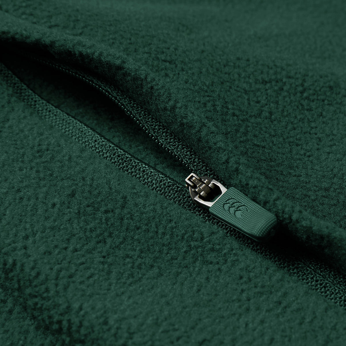 Close-up of the Ireland 26 Retro Fleece 1/4 Zip by Canterbury in green, showing the textured fleece fabric and a partially closed branded zipper pull.