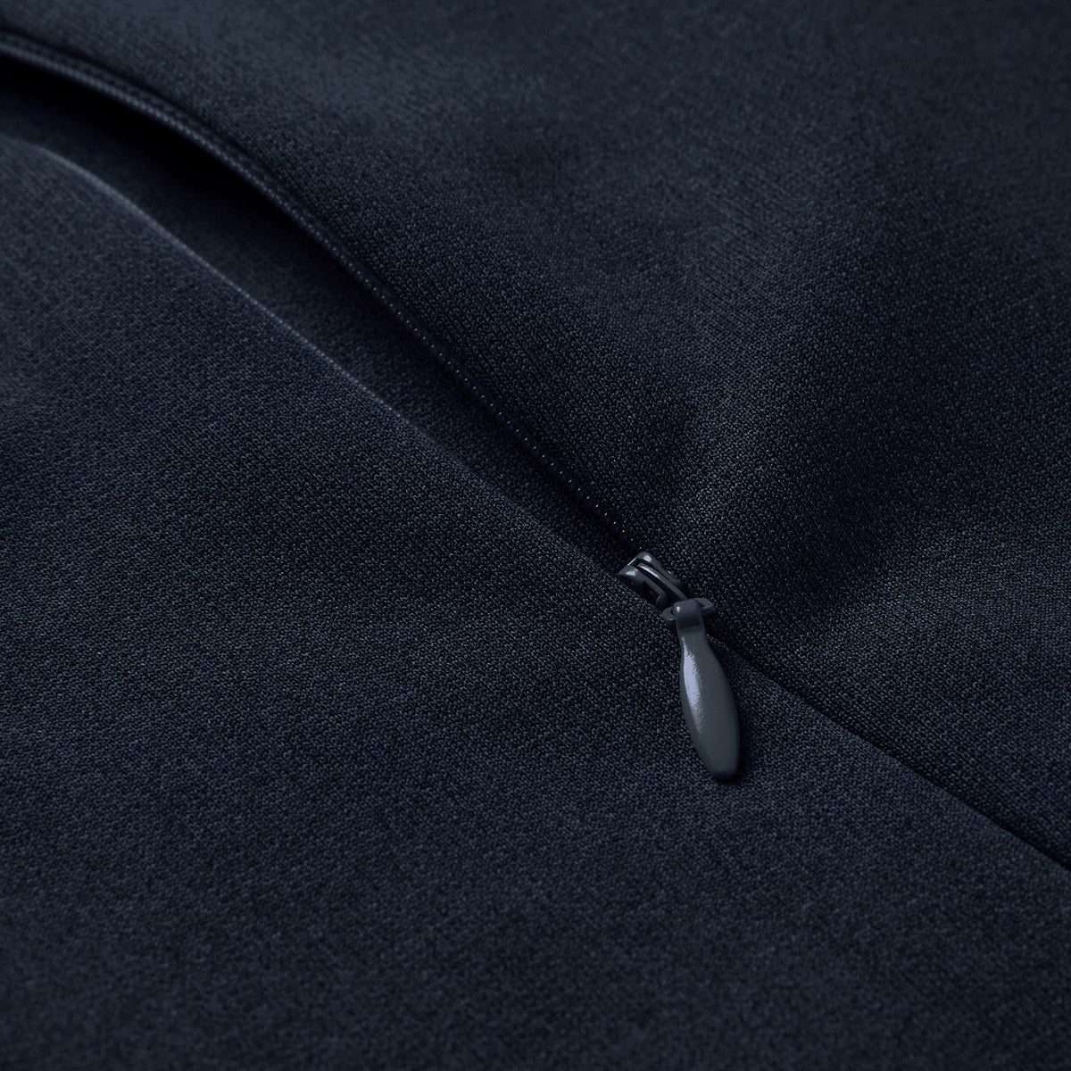 Close-up of a black zipper partially closed on dark fabric, highlighting the zipper pull and material texture on the Ireland 26 Hybrid Padded Jacket by Canterbury.