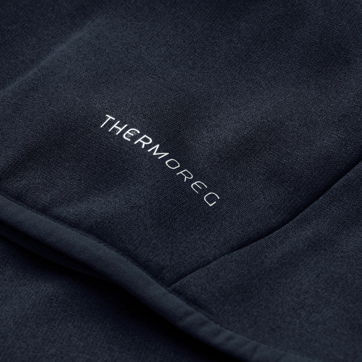 Close-up of a dark fabric with the word “THERMOREG” printed in white, highlighting Canterbury’s innovative ThermoReg technology featured in the Ireland 26 Hybrid Padded Jacket, designed for effective temperature regulation.