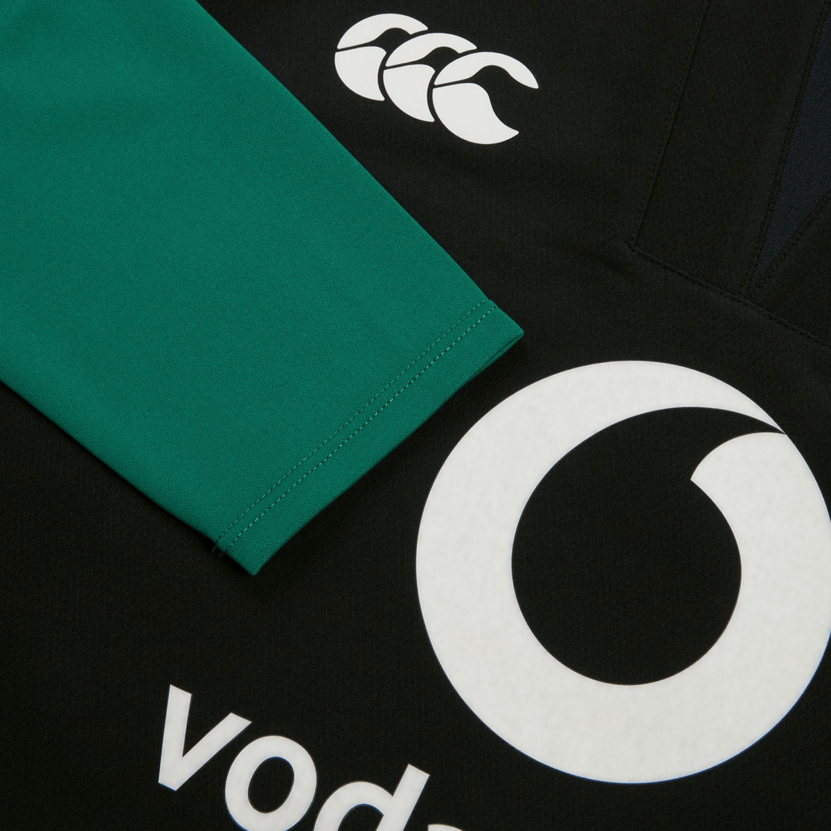 Close-up of the Ireland 25/26 Tech Drill Top by Canterbury, a black and green rugby top showcasing the Canterbury logo and a partial Vodafone logo.