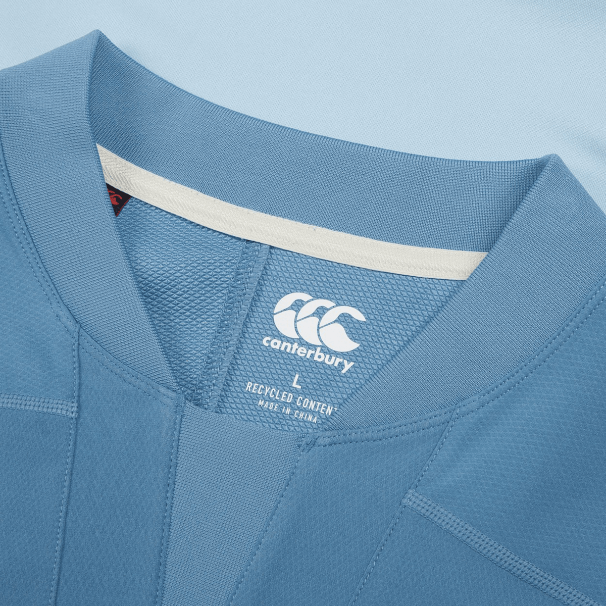 Close-up of the Ireland 25/26 Tech Drill Top by Canterbury, highlighting the blue fabric, logo, clothing tag, and detailed stitching—demonstrating signature Canterbury quality.