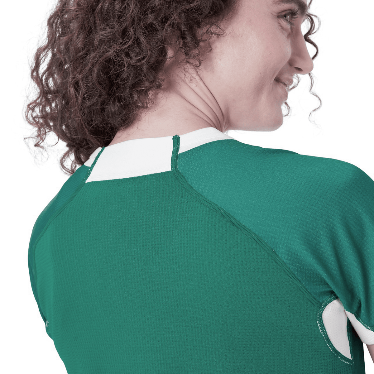 A person with curly hair is seen from behind wearing the Women&#39;s Ireland WIRFU Home Pro Jersey by Canterbury, displaying the Official IRFU crest in a chic green and white design.