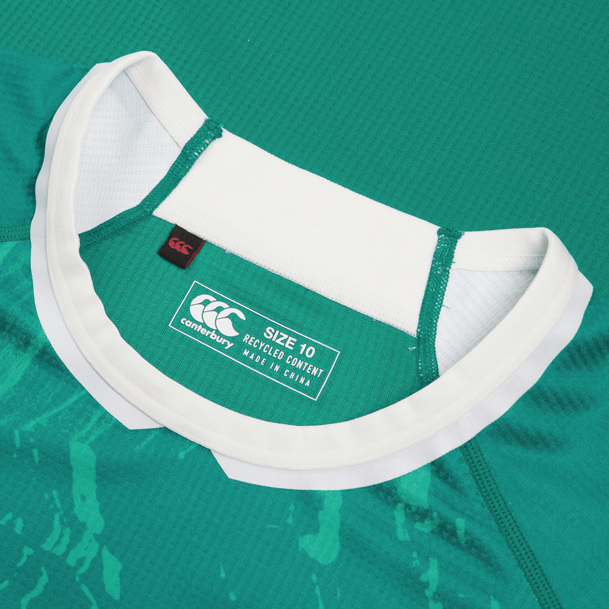 Close-up of a green Women&#39;s Ireland WIRFU Home Pro Jersey by Canterbury with a white collar. It features the Official IRFU crest, &quot;Canterbury&quot; label, &quot;Size 10,&quot; &quot;Recycled Content,&quot; and &quot;Made in China.&quot; VapoDri technology enhances comfort.