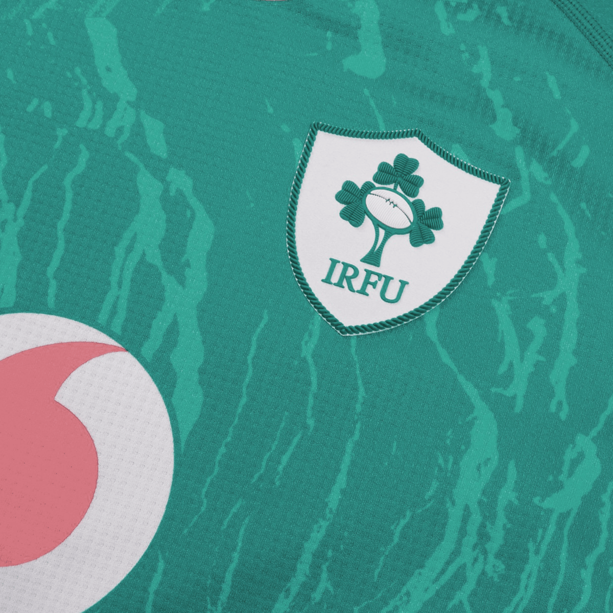 Close-up of the Women&#39;s Ireland 24 Home Pro Jersey by Canterbury, featuring the iconic IRFU logo with three shamrocks and a rugby ball, plus a touch of a pink and white emblem. Made with VapoDri technology, this jersey ensures comfort and performance for Ireland Women&#39;s Rugby.
