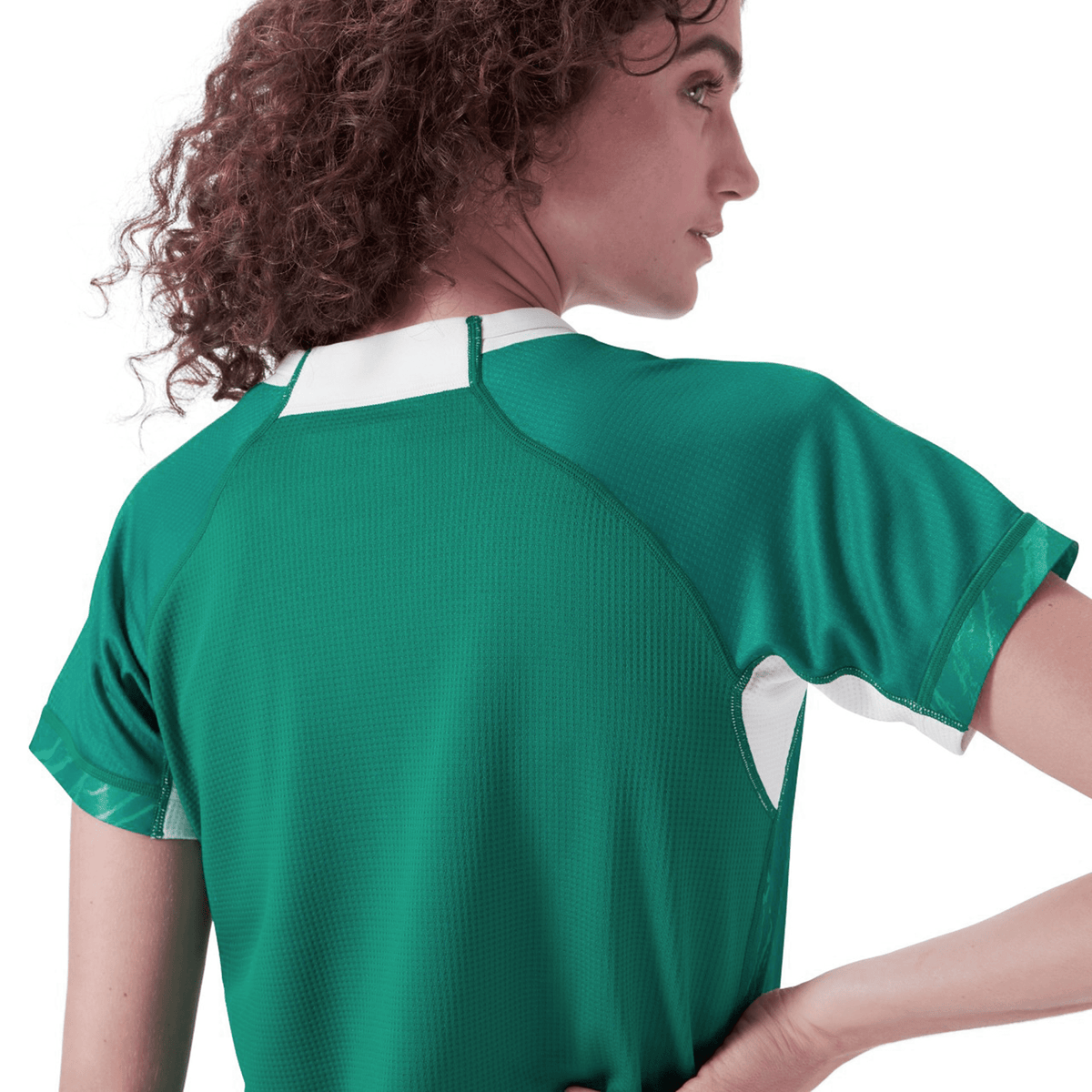 A person with curly hair, facing away from the camera, showcases the Women&#39;s Ireland 24 Home Pro Jersey by Canterbury, featuring green VapoDri technology.