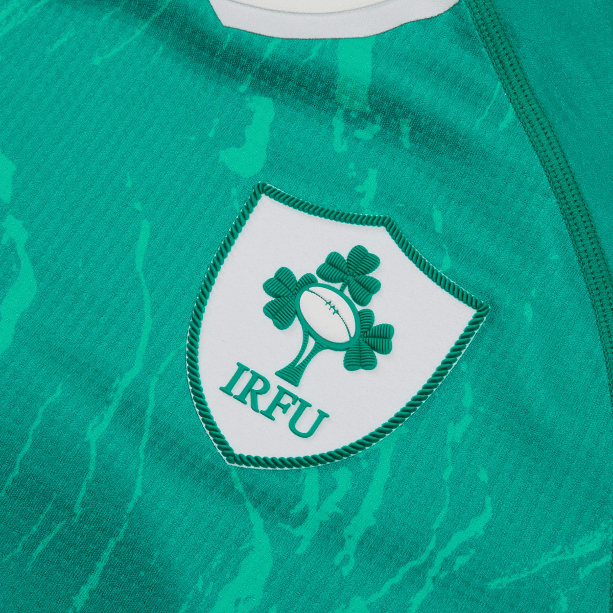 Close-up of the Youth Ireland 24 Home Pro Jersey by Canterbury in vibrant green, featuring the IRFU Crest with a rugby ball and three shamrocks. Enhanced with VapoDri Technology, this Canterbury jersey guarantees optimal comfort and performance on the field.