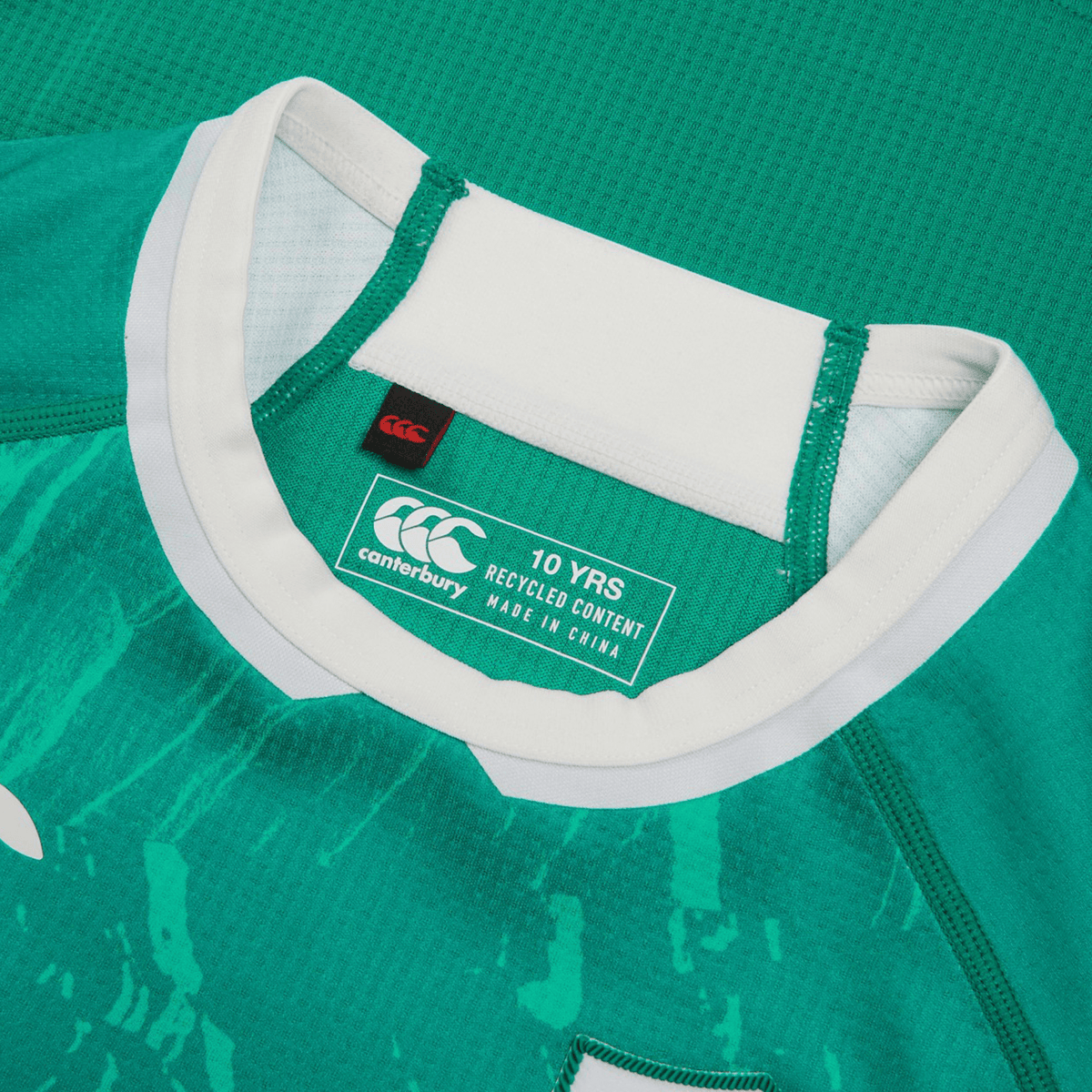 Close-up of a green Youth Ireland 24 Home Pro Jersey by Canterbury, showcasing VapoDri Technology and recycled content. It features a white collar, label, and IRFU Crest. Made in China.