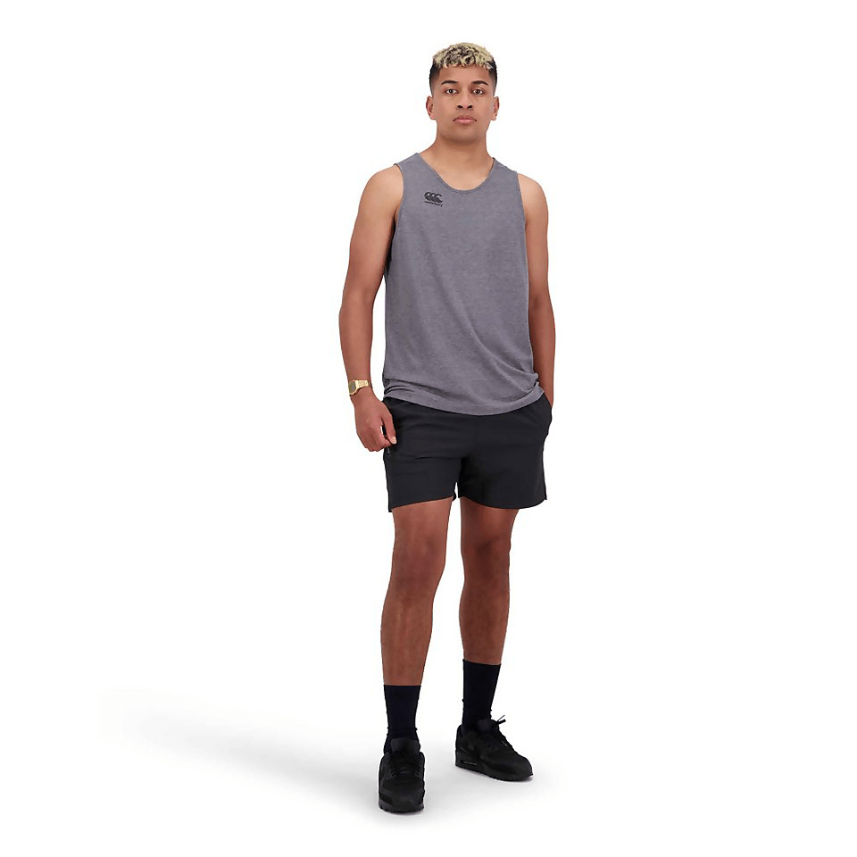 A man sporting the Canterbury Tempo Vapodri Singlet, made of recycled polyester fabric, in a grey tank top and black shorts.
