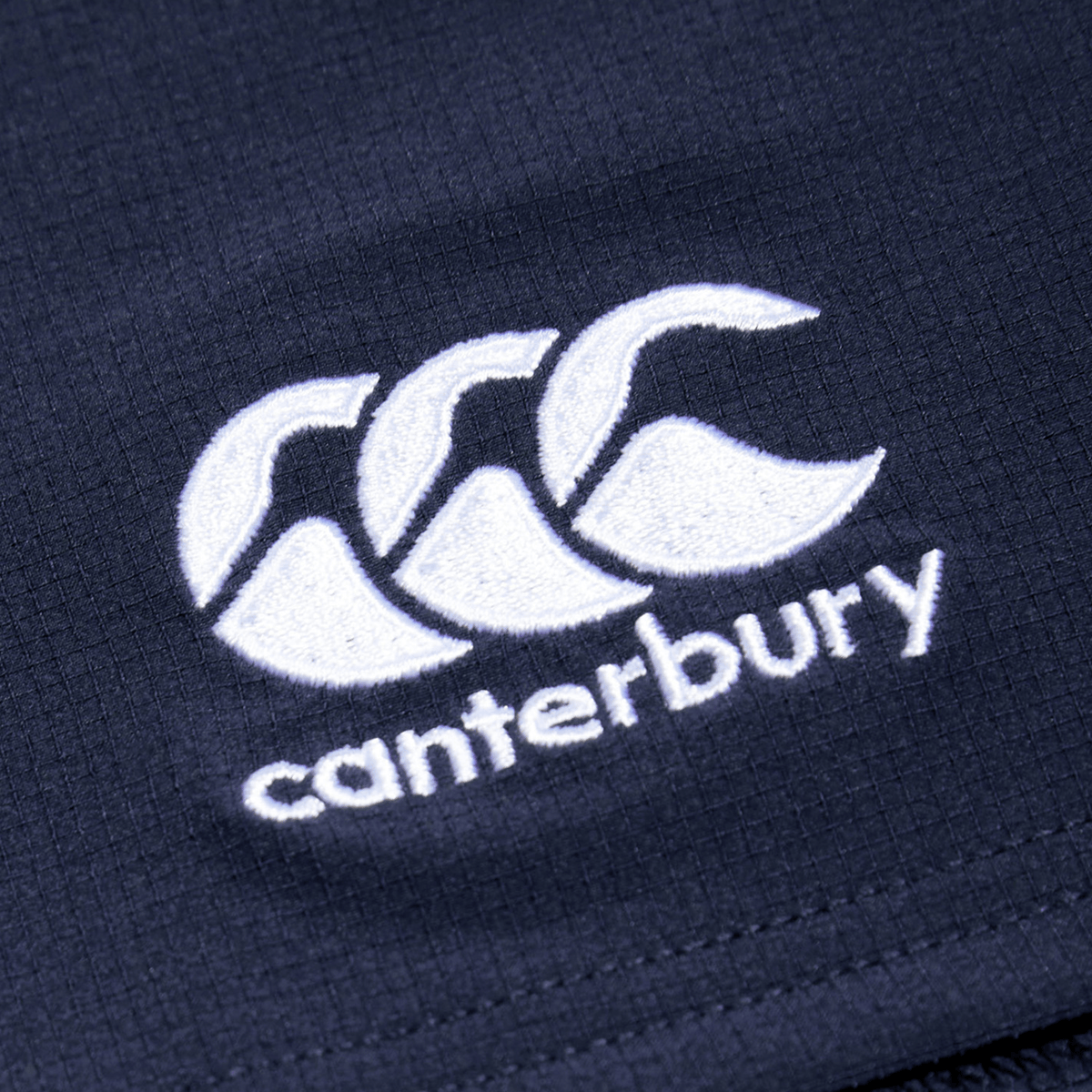 Navy blue fabric with a white "Canterbury" logo of three overlapping curves, ideal for the Canterbury Yokohama Short 3-Pack Bundle by Bundle Canterbury.