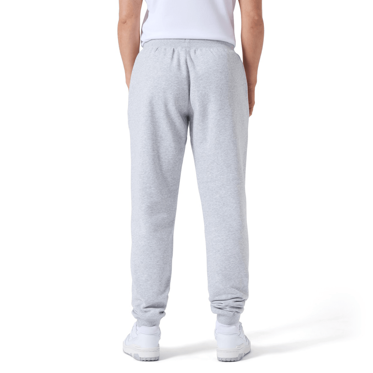 Person wearing gray Women&#39;s Leisure Sweatpant by Canterbury and white sneakers, standing with their back to the camera on a plain background. The Canterbury logo is subtly visible, hinting at the premium quality of the cotton blend fleece.