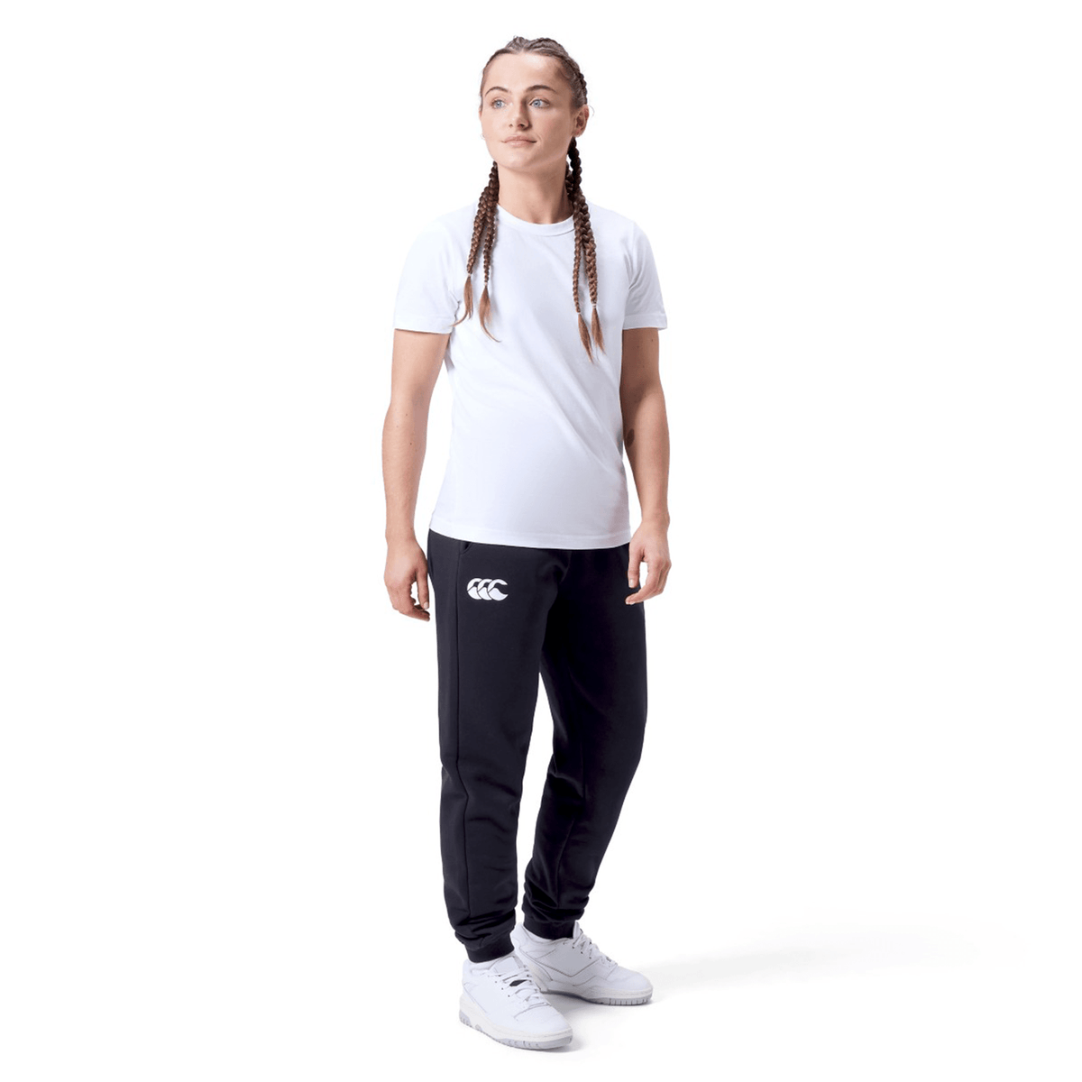 A person wears a white t-shirt, Women&#39;s Leisure Sweatpant by Canterbury in a cotton blend fleece, and white sneakers, standing against a plain white background.