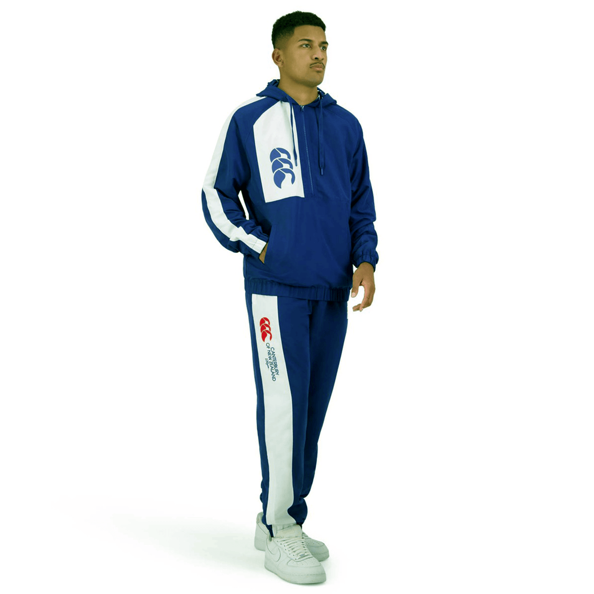 Person wearing a blue and white athletic tracksuit, standing against a plain white background. The tracksuit, identified as the Canterbury Legends Stadium Track Pant, features branded Canterbury logos on the chest and leg areas.