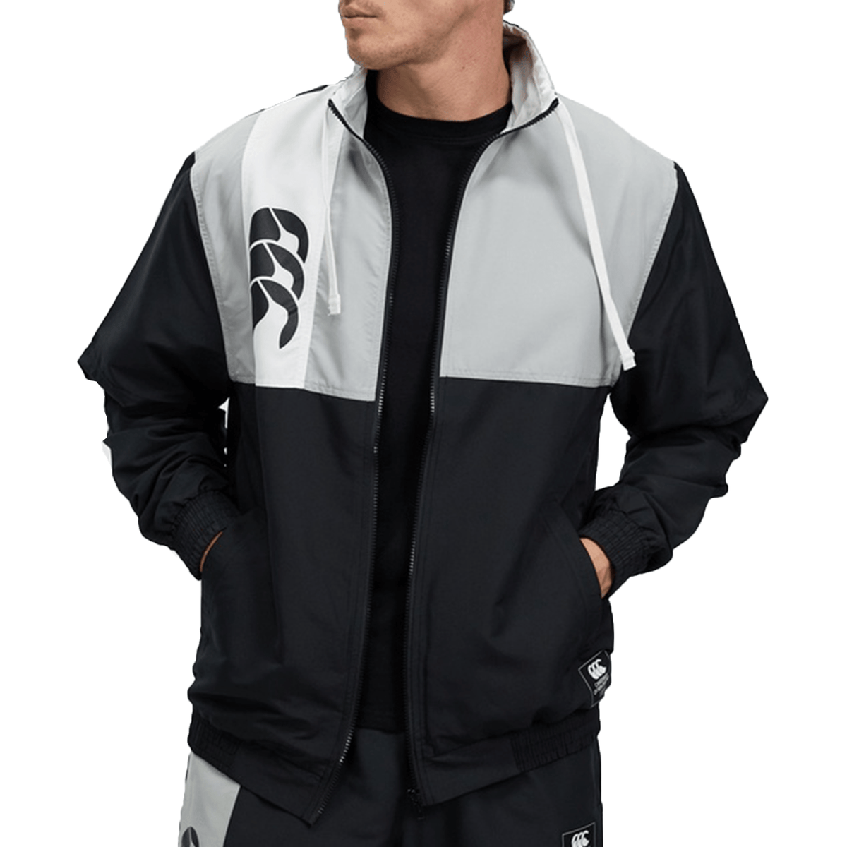 Man wearing a Canterbury Legends Woven Track Jacket in black and white with a logo on the left chest, zipped halfway, against a plain background.