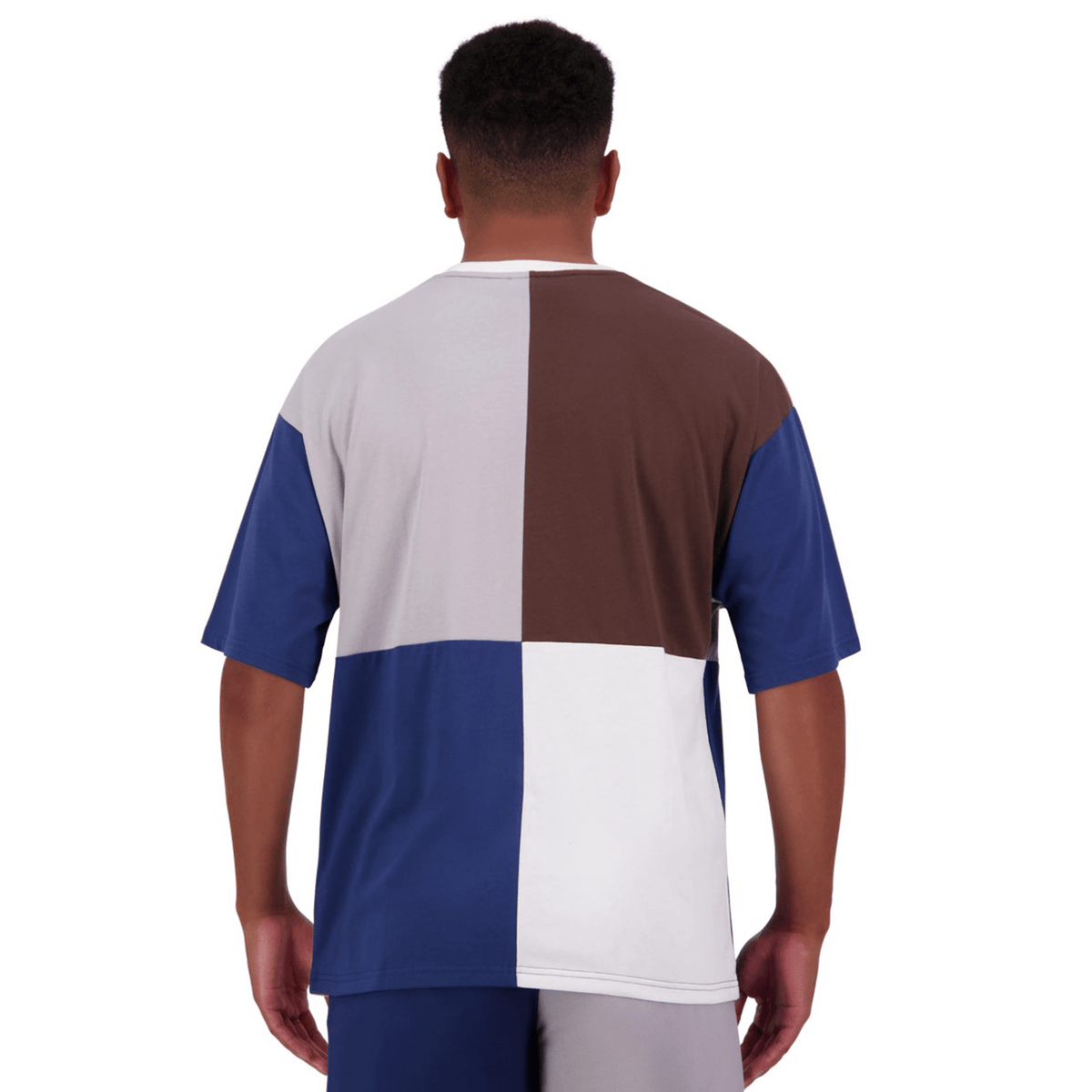 A man viewed from the back wearing a Canterbury Harlequin Block T-Shirt by Canterbury, featuring an asymmetric design in brown, gray, blue, and white.