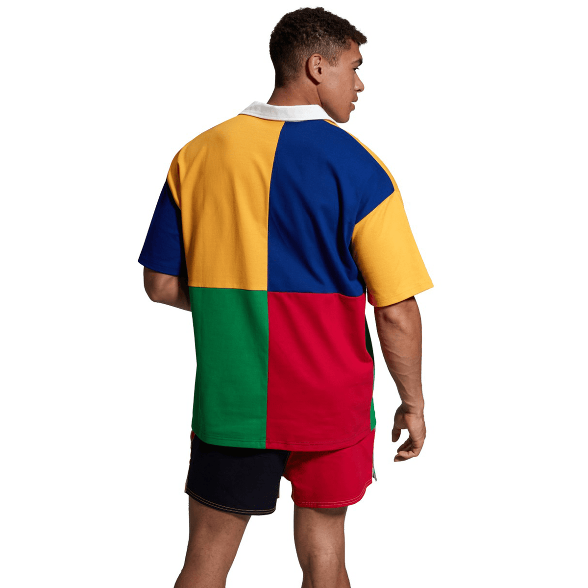 A person with short hair, wearing a Canterbury Harlequin Rugby Jersey and red shorts, is standing and facing away.