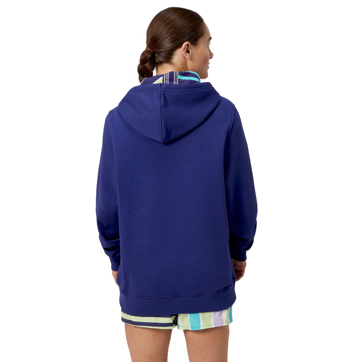 A person in a blue Canterbury Women&#39;s Uglies Hoodie and striped shorts, facing away. Their hair is tied back in a braid, highlighting the relaxed fit of this women&#39;s cut garment from Canterbury.