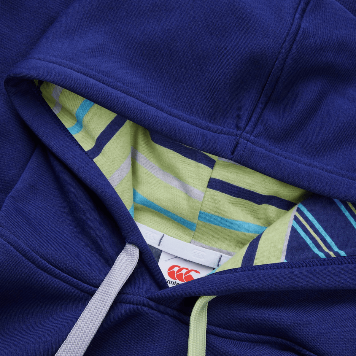 Close-up of a Canterbury Women&#39;s Uglies Hoodie featuring a blue design, striped inner lining, and white drawstrings with the tag displaying the red Canterbury logo inside the hood.