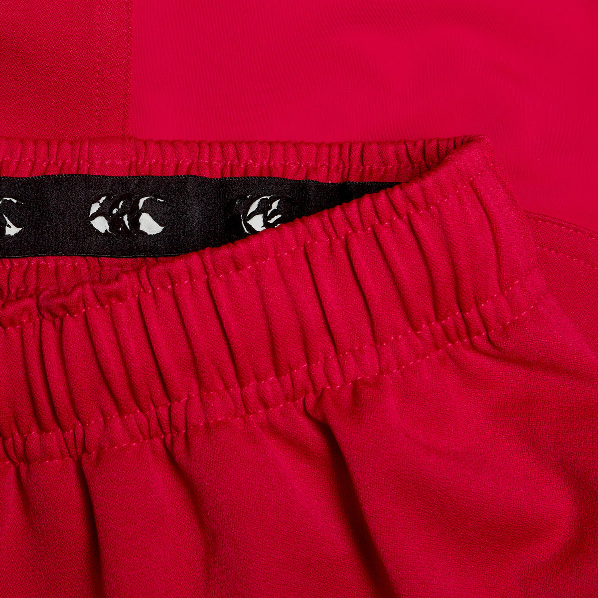 Close-up of the elastic waistband of the Canterbury Advantage Short 2.0 in vibrant red, showcasing intricate thread details and inner lining. This design from Canterbury incorporates performance sustainability with recycled content for eco-conscious comfort.