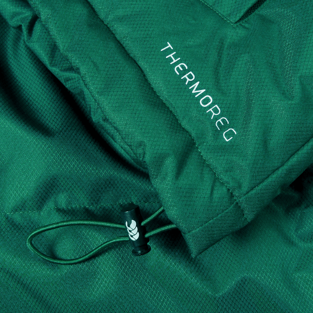 Close-up of an Ireland 24 Puffer Jacket by Canterbury in green, with the word &quot;THERMOREG&quot; printed on it, featuring a drawstring with a black plastic toggle.