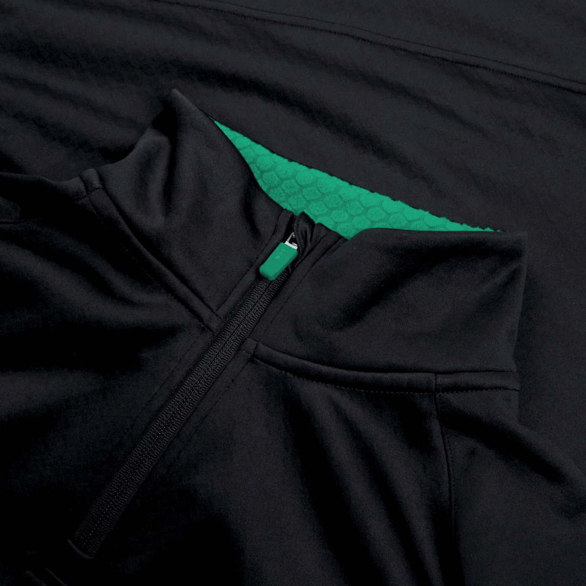 Close-up of the Ireland 1/4 Zip Training Top 25/26 by Canterbury in black, featuring a green textured inner lining with Thermoreg technology, shown against a matching dark fabric background.