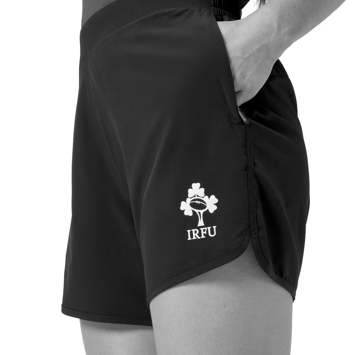 A person wearing Canterbury Women&#39;s Ireland 25/26 Woven Gym Shorts with a hand in the pocket, shown from waist to mid-thigh—ideal for Ireland women&#39;s rugby or as comfortable Canterbury gym shorts.