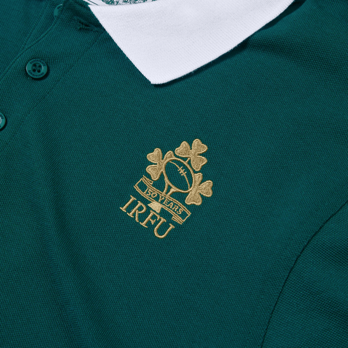 The Ireland 150th Anniversary Polo by Canterbury is a green rugby shirt with a white collar, featuring an embroidered logo of a rugby ball and shamrocks. Labeled "150 Years IRFU," this polo is essential for rugby fans celebrating Ireland's 150th Anniversary with pride.