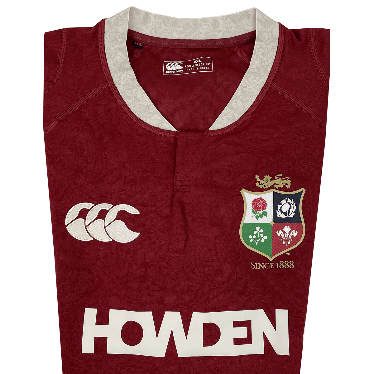 The British &amp; Irish Lions 2025 Players Authentic Jersey by Canterbury showcases a red design with a white collar, Lions emblem, and Canterbury logo alongside "HOWDEN" text. It features intricate patterns and "Since 1888" text, honoring its legacy—ideal for the 2025 tour.