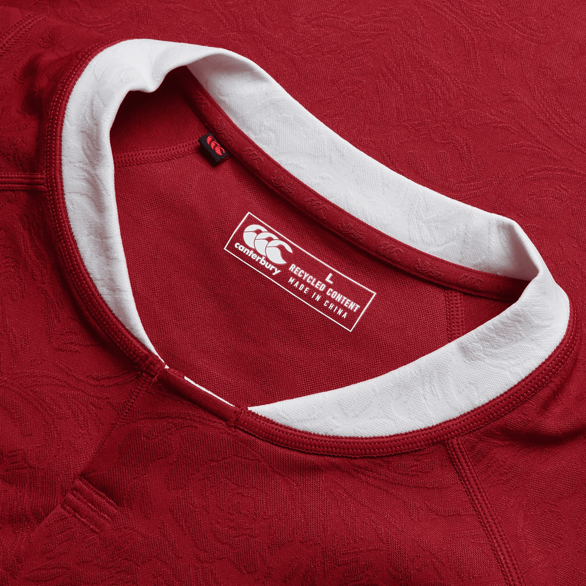 Close-up of a red British &amp; Irish Lions 2025 Players Jersey by Canterbury sports shirt, featuring a white collar and clearly visible label. It emphasizes the moisture-wicking fabric crafted in China from recycled materials, offering optimal comfort and style both on and off the field.