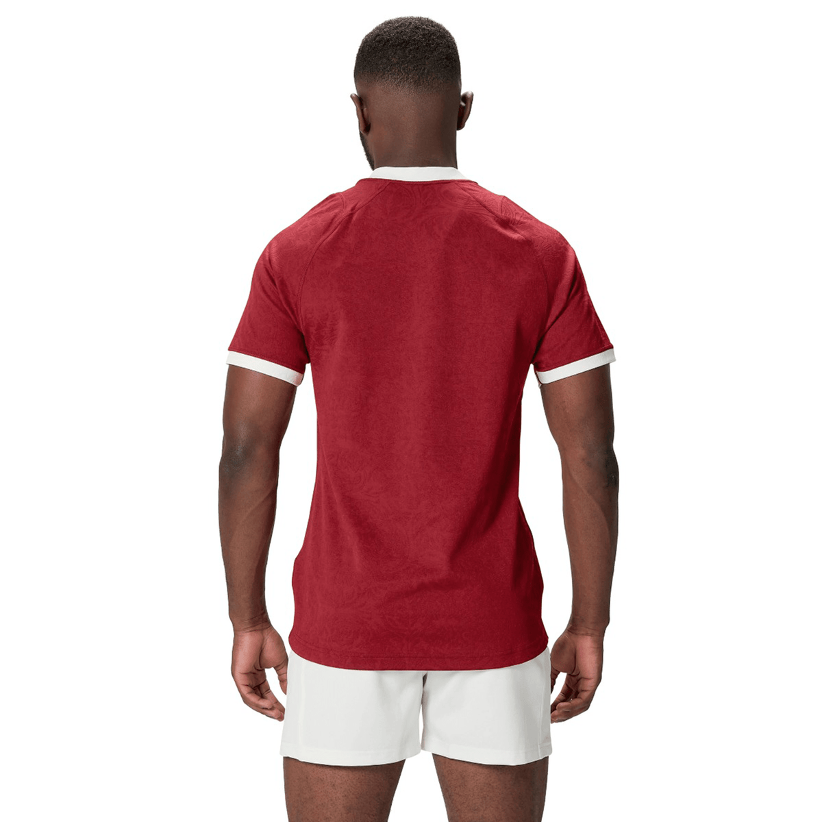 A person in a red shirt and white shorts, akin to the British &amp; Irish Lions 2025 Players Jersey by Canterbury, stands with their back to the camera against a plain white background.