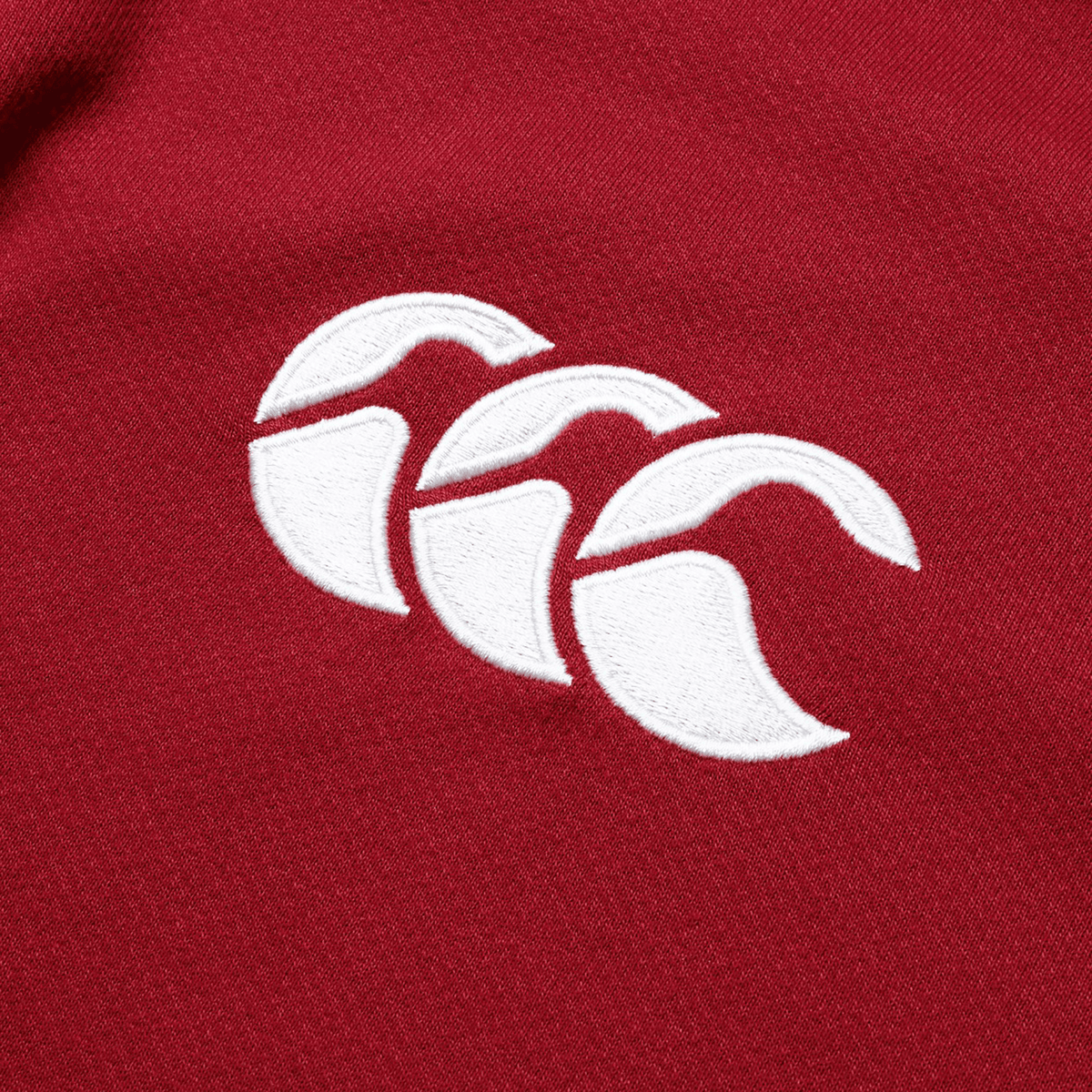 Close-up of the British &amp; Irish Lions 2025 Long Sleeve Classic Jersey by Canterbury, showcasing red fabric with a white embroidered logo featuring three overlapping arches.