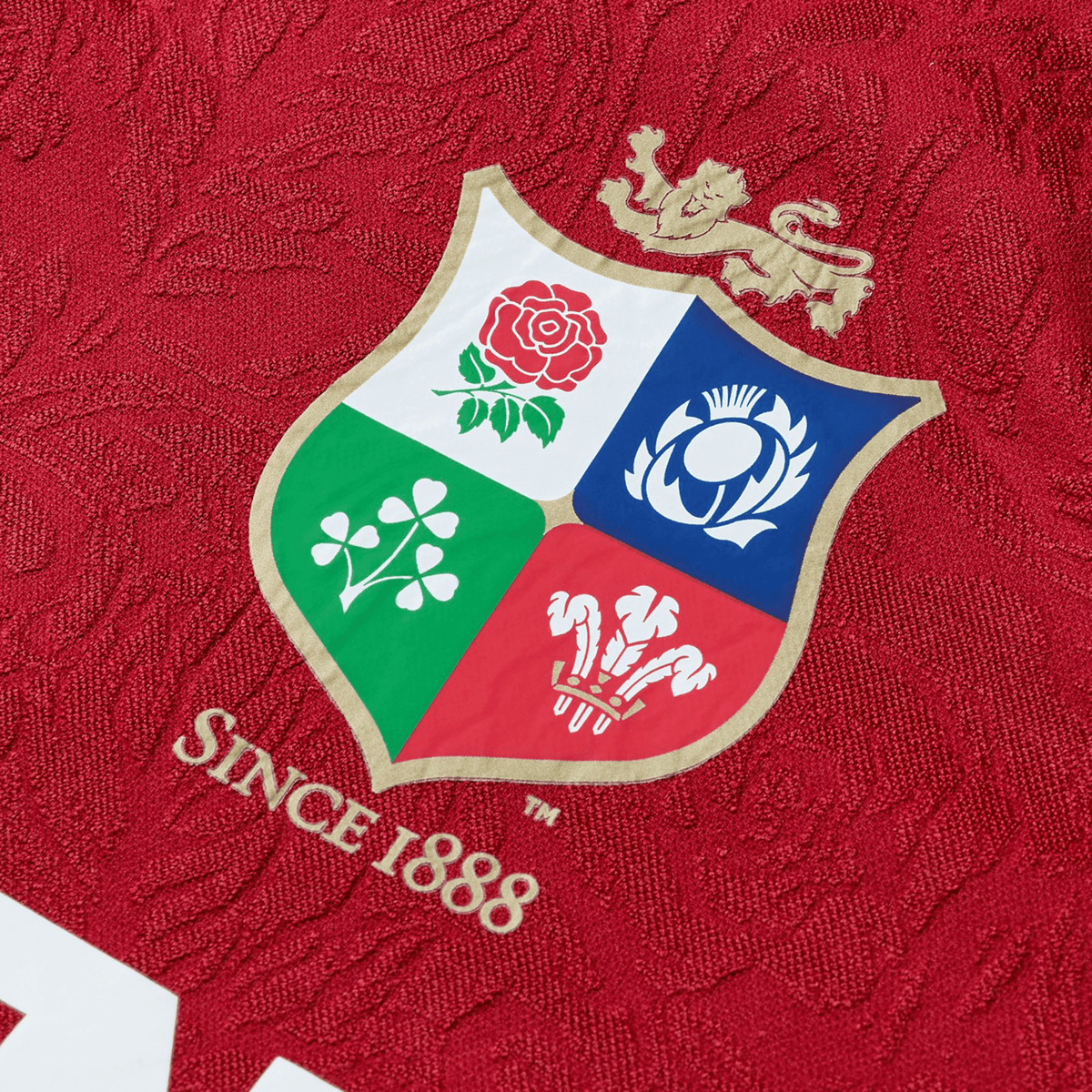 The Youth British &amp; Irish Lions 2025 Players Jersey by Canterbury, colored red and detailed with a crest of a lion, rose, thistle, shamrock, and three feathers, boasts ergonomic paneling and moisture-wicking fabric. It proudly features &quot;Since 1888&quot; for lasting comfort and style.