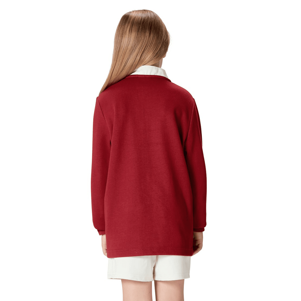 Rear view of a child wearing the Youth British &amp; Irish Lions 2025 Long Sleeve Classic Jersey by Canterbury in red, paired with white shorts, with long hair cascading down their back.