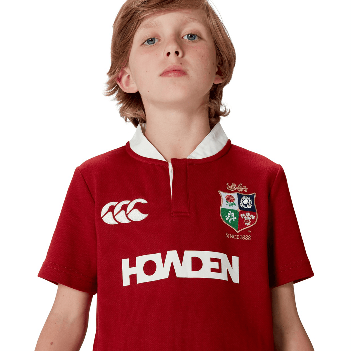 A child in a Youth British &amp; Irish Lions 2025 Classic Jersey by Canterbury, featuring a red color, white logo and text, and short sleeves, is looking upwards.