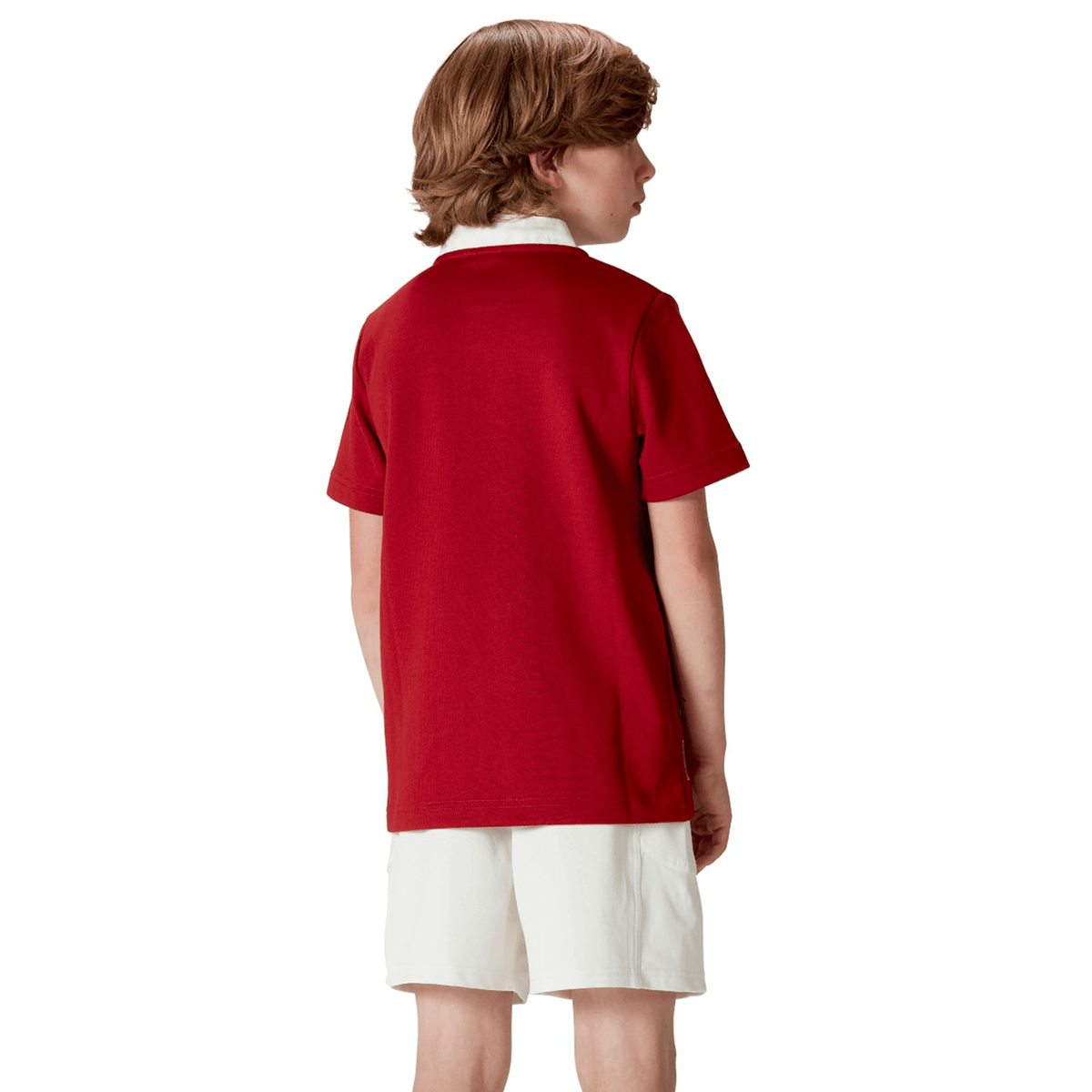 A brown-haired child, wearing the Youth British &amp; Irish Lions 2025 Classic Jersey by Canterbury and white shorts, stands facing away.
