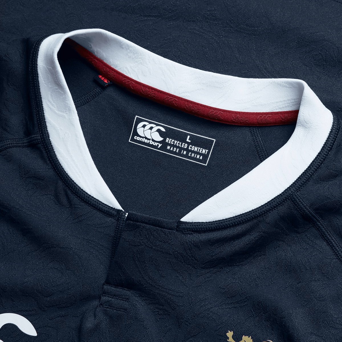 A close-up of the British &amp; Irish Lions 2025 Training Jersey by Canterbury showcases its blue design with white collar details, ergonomically designed panels, and a "L" size label for large. Proudly manufactured in China.