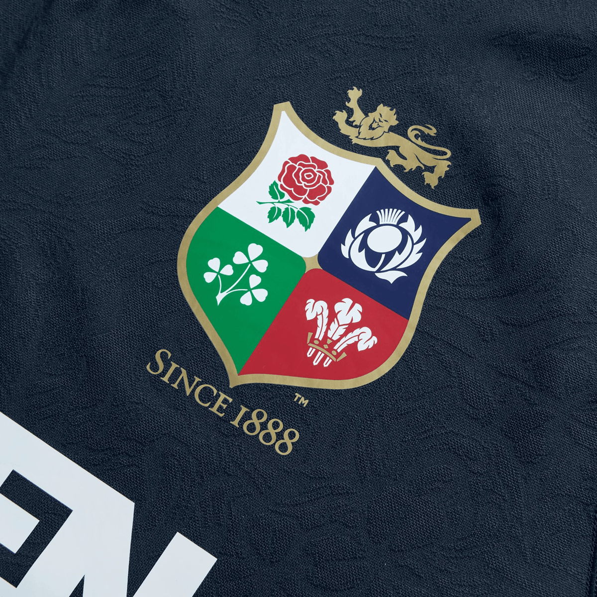 The British &amp; Irish Lions 2025 Training Jersey by Canterbury is a replica training jersey made from recycled polyester, featuring a shield with four symbols—a rose, thistle, shamrock, and three feathers—with "Since 1888" proudly displayed beneath it.
