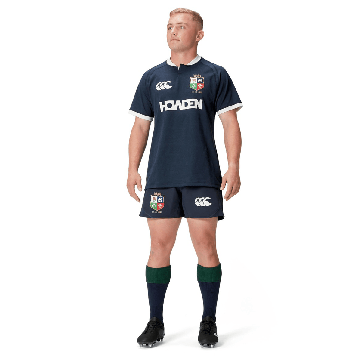 A person in the British &amp; Irish Lions 2025 Training Jersey by Canterbury, a navy rugby uniform with logo, stands with hands at sides, looking upward. This attire from Canterbury is inspired by the classic style of the British &amp; Irish Lions and features ergonomically placed panels for enhanced movement and comfort during play.