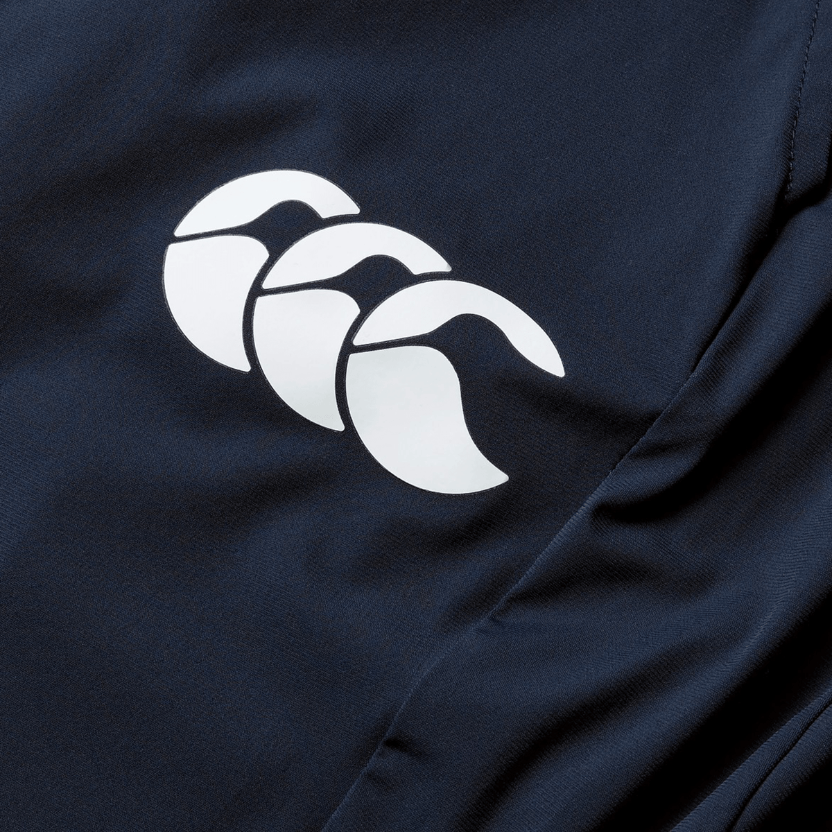 Close-up of a navy quick-drying fabric on the British &amp; Irish Lions 2025 Everest Woven Pant by Canterbury, showcasing a white logo with three overlapping, curved shapes.